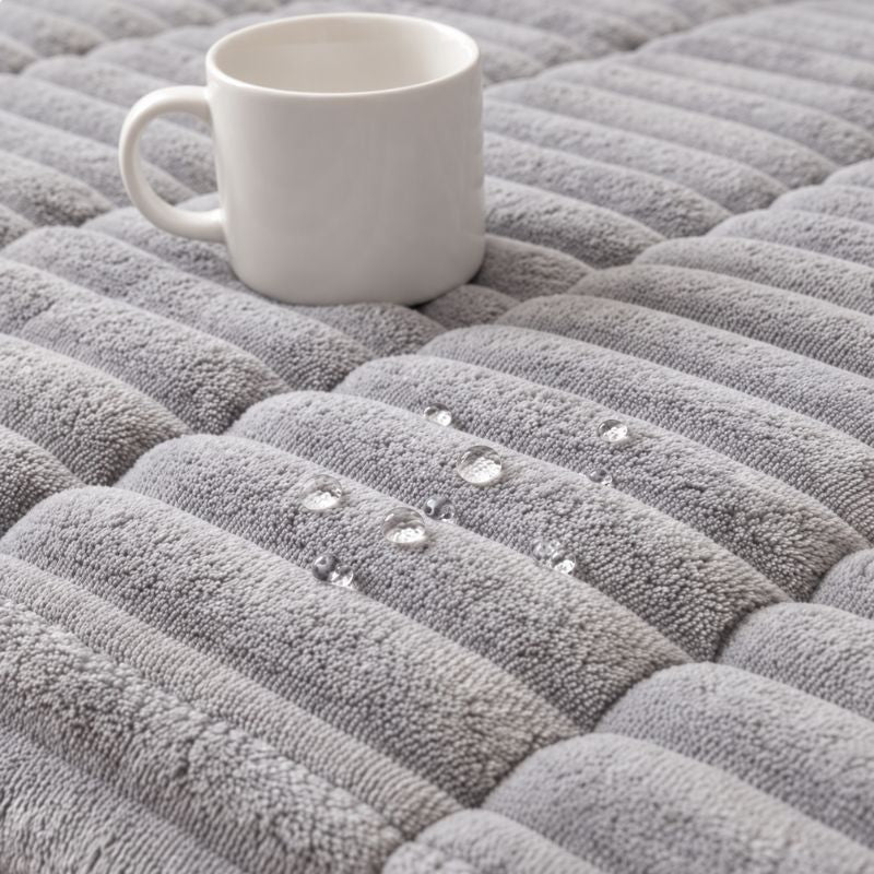 Tissu déperlant de la housse CanapéIntégral™ : les gouttes restent en surface à côté d'une tasse