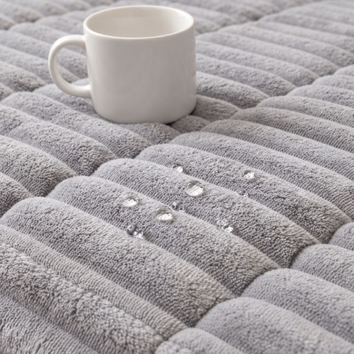 Tissu déperlant de la housse CanapéIntégral™ : les gouttes restent en surface à côté d'une tasse